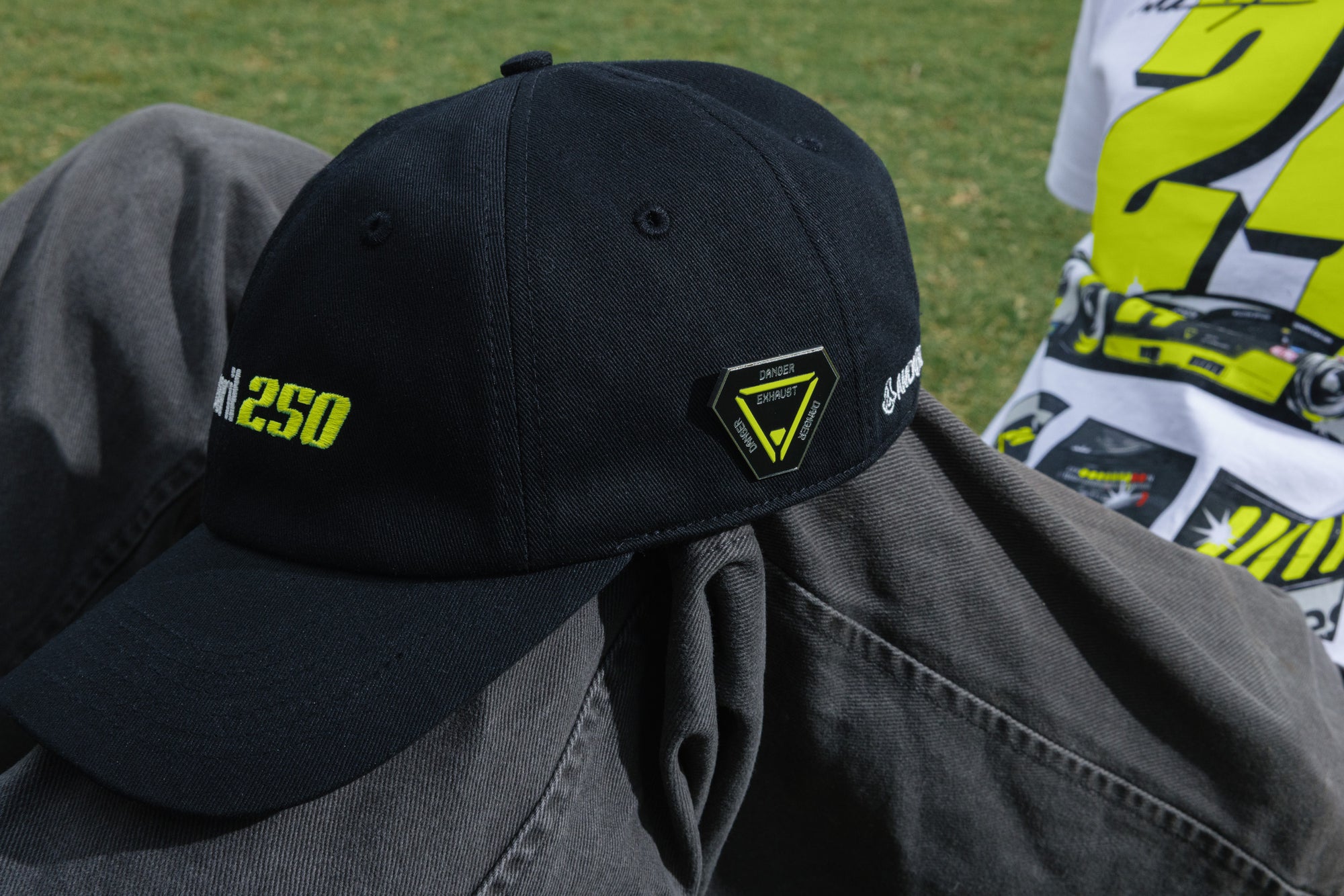 Black cap with yellow text and logo on a person wearing a gray jacket, with a blurred background.